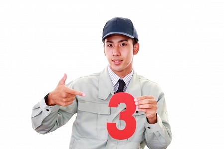 作業服の男性が数字の3を示している様子